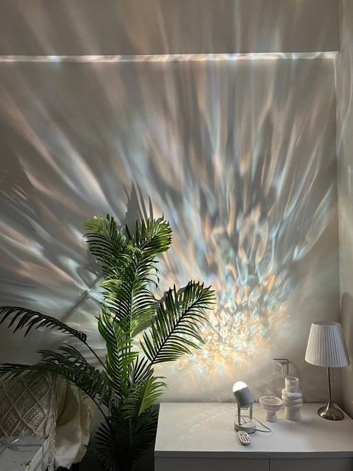 Lampe de table MAVI projetant des ondulations lumineuses dynamiques aux couleurs douces sur un mur.